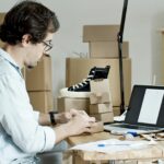 Businessman packing products and managing an online store from his desk with a laptop.